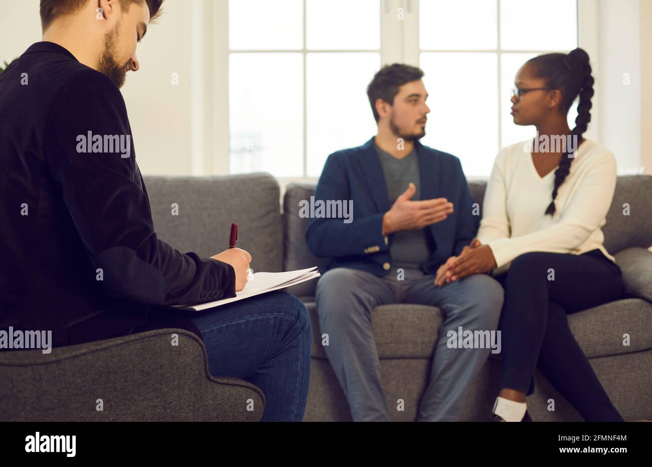 Family consultant writing notes while couple discussing relationship problem Stock Photo