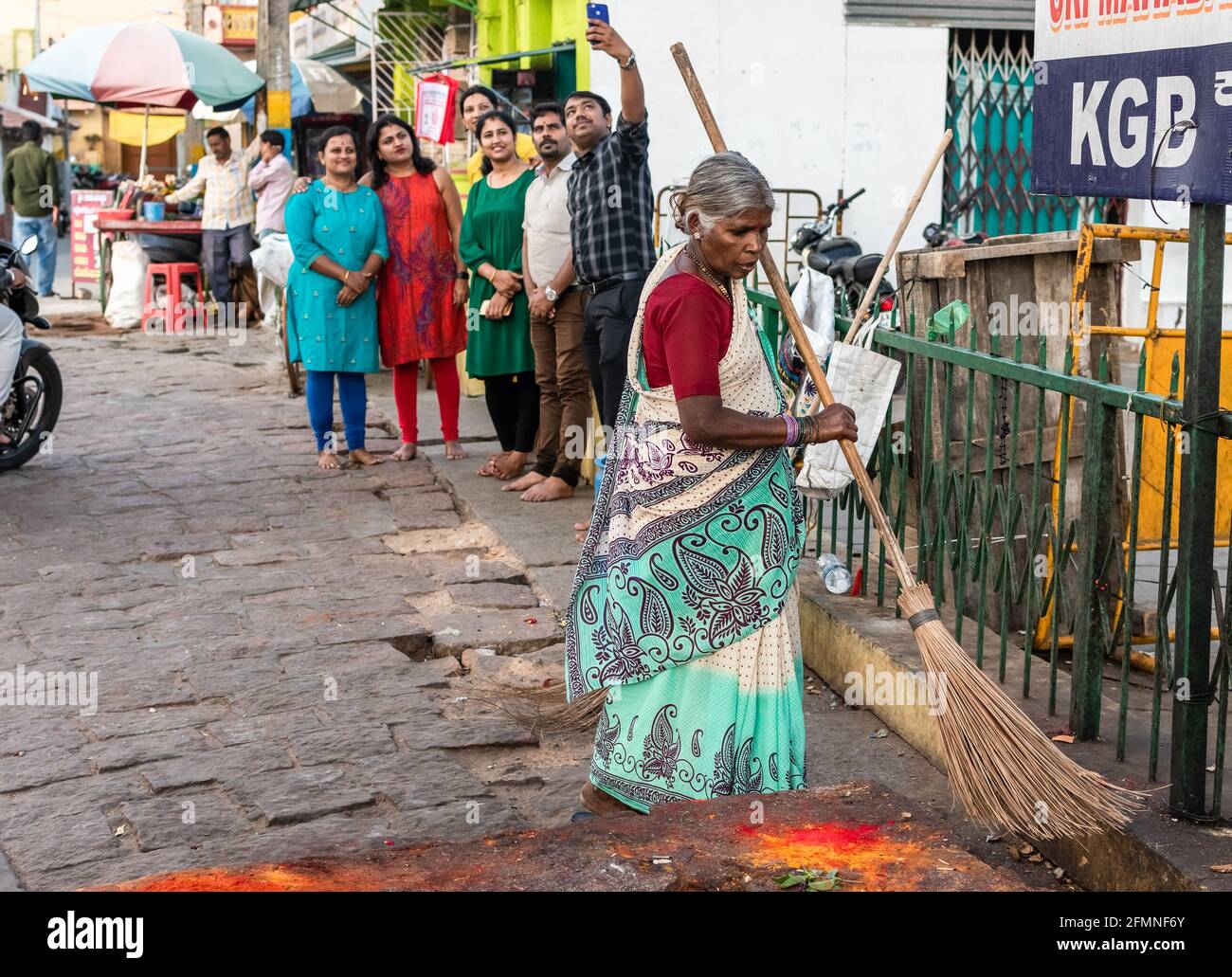 Mysuru, Karnataka, India - January 2019: An elderly Indian woman sanitation worker sweeping the streets with a large wooden straw broomstick in the ci Stock Photo