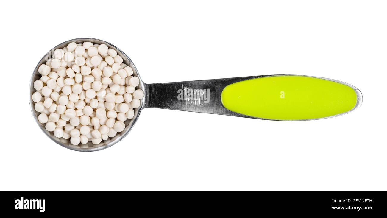 top view of uncooked ptitim (pearl couscous) in measuring spoon cutout on white background Stock Photo