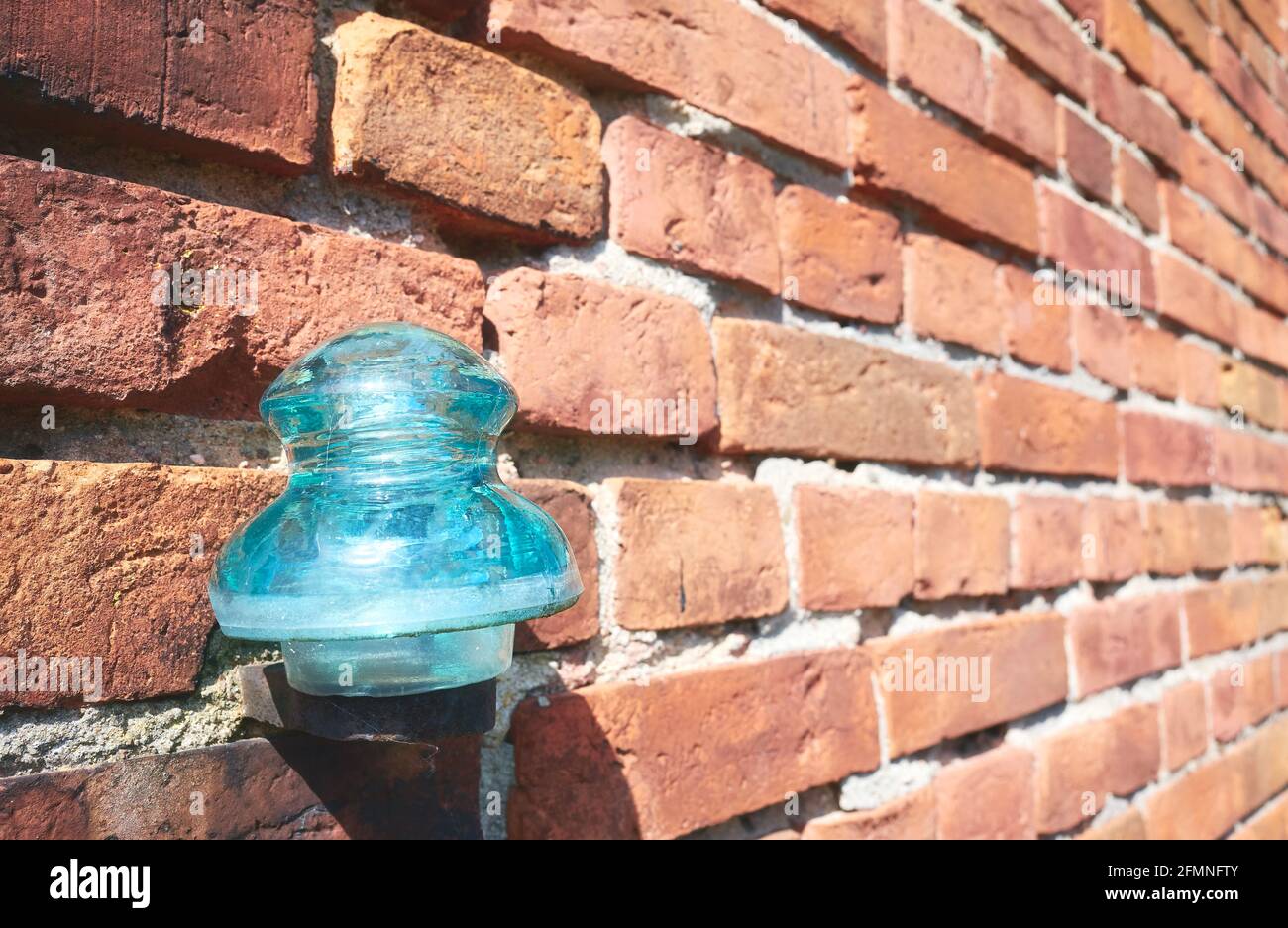 Close up picture of an old glass electrical insulator on a brick wall, selective focus. Stock Photo