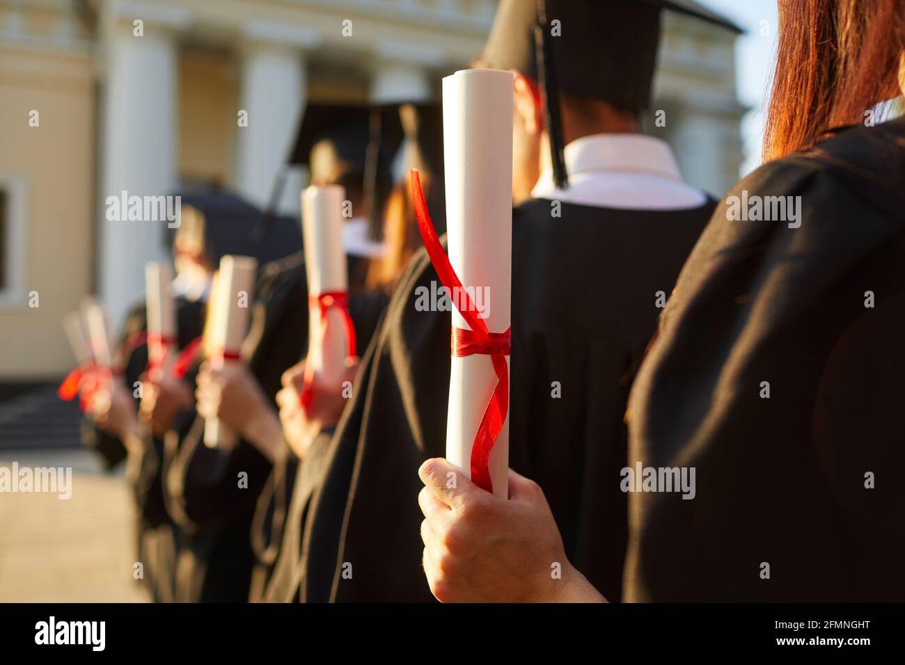Graduate.Selective focus on degree diploma certificate in hand of student standing in row Stock Photo