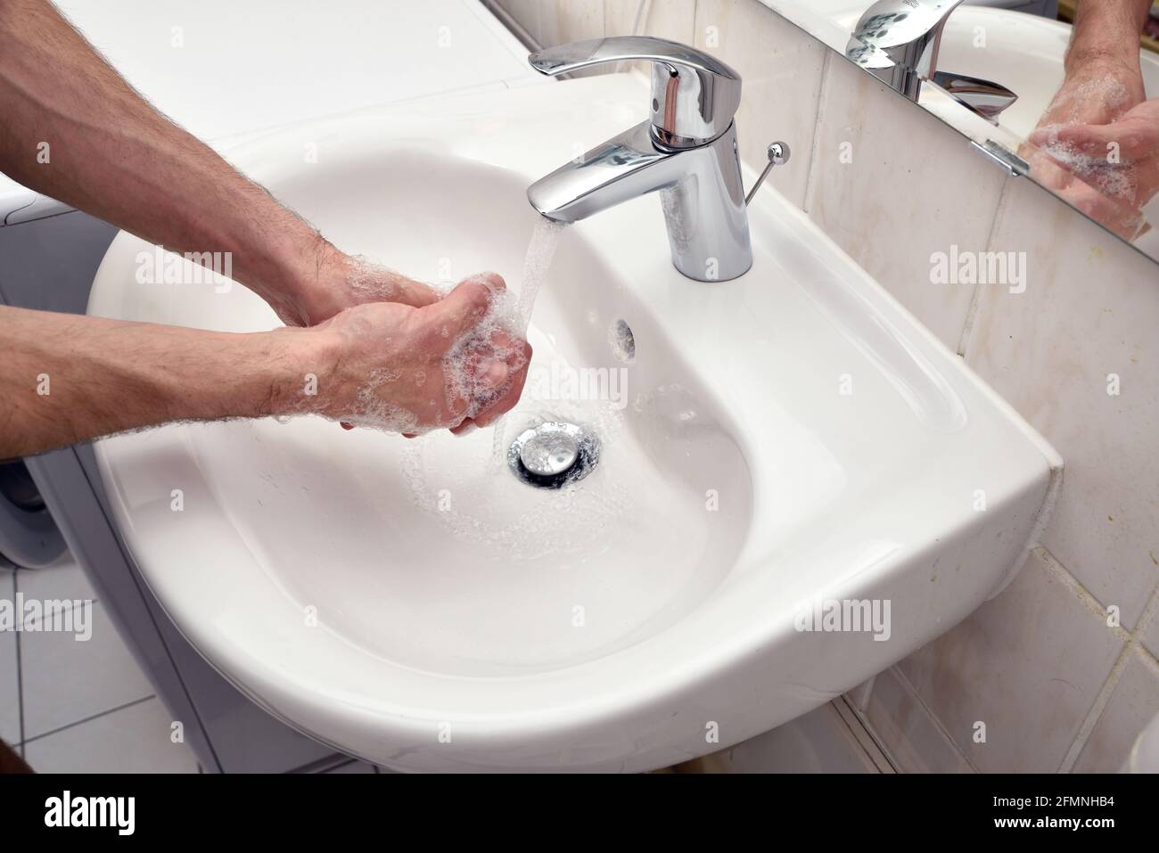 male washing hands to prevent corony virus disease spreading desinfection with soap and water Stock Photo