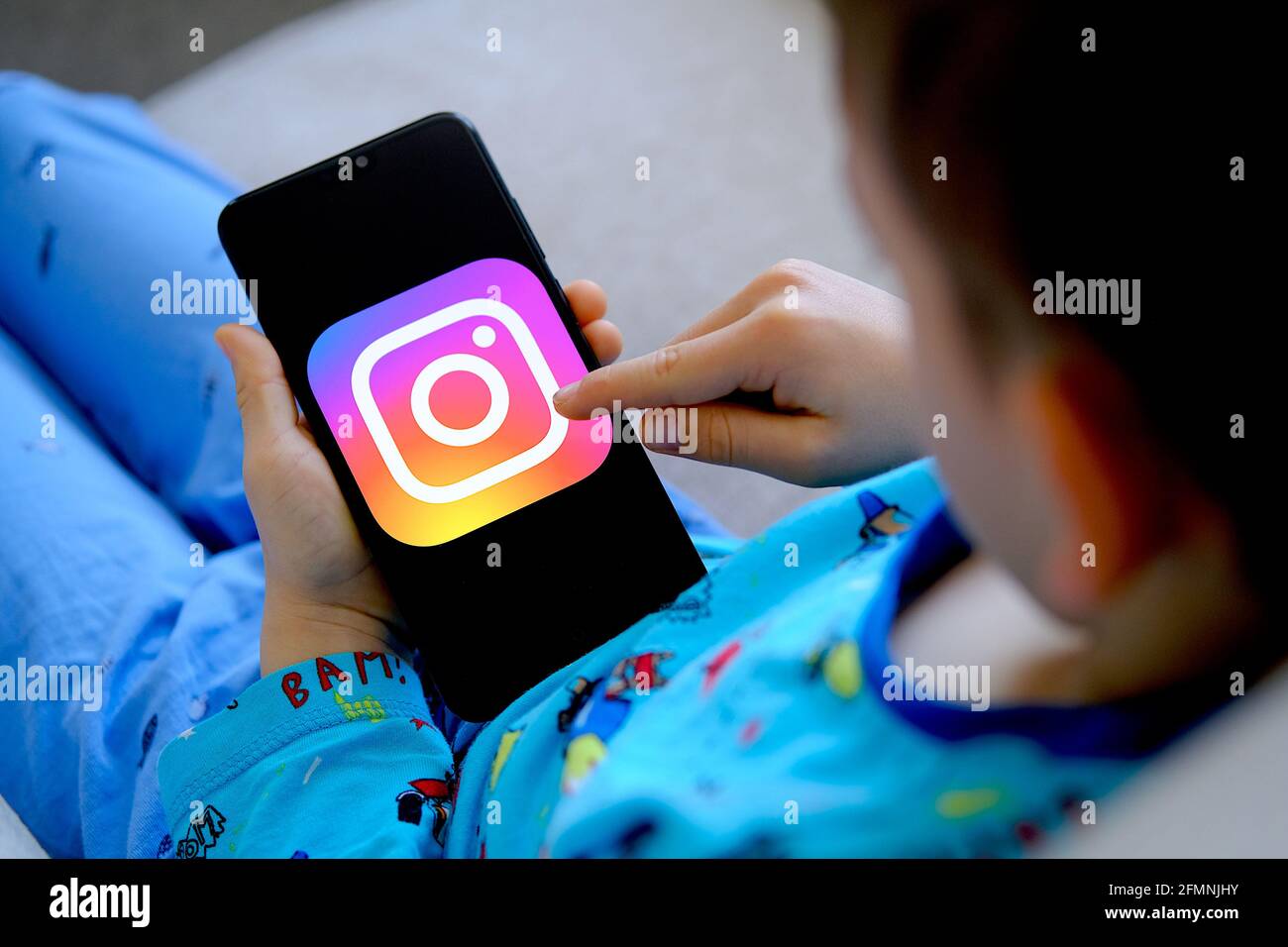 Child holding device with instagram app in his hands. Concept for child privacy and data protection in social media. Stafford, United Kingdom, May 11, Stock Photo