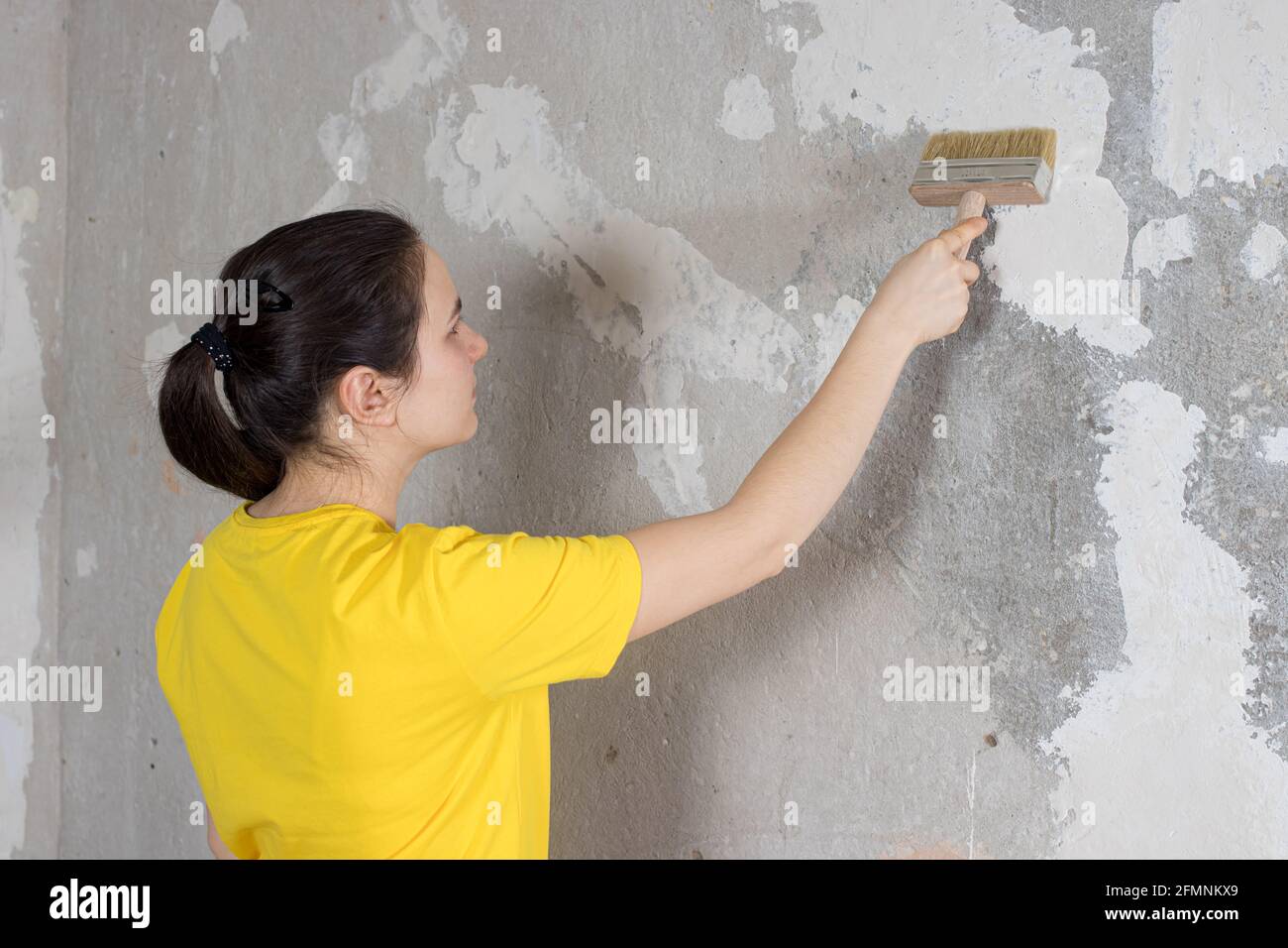 A woman repairman puts wallpaper glue on the wall. The wallpaper in the  house and repair with their own hands yourself Stock Photo - Alamy