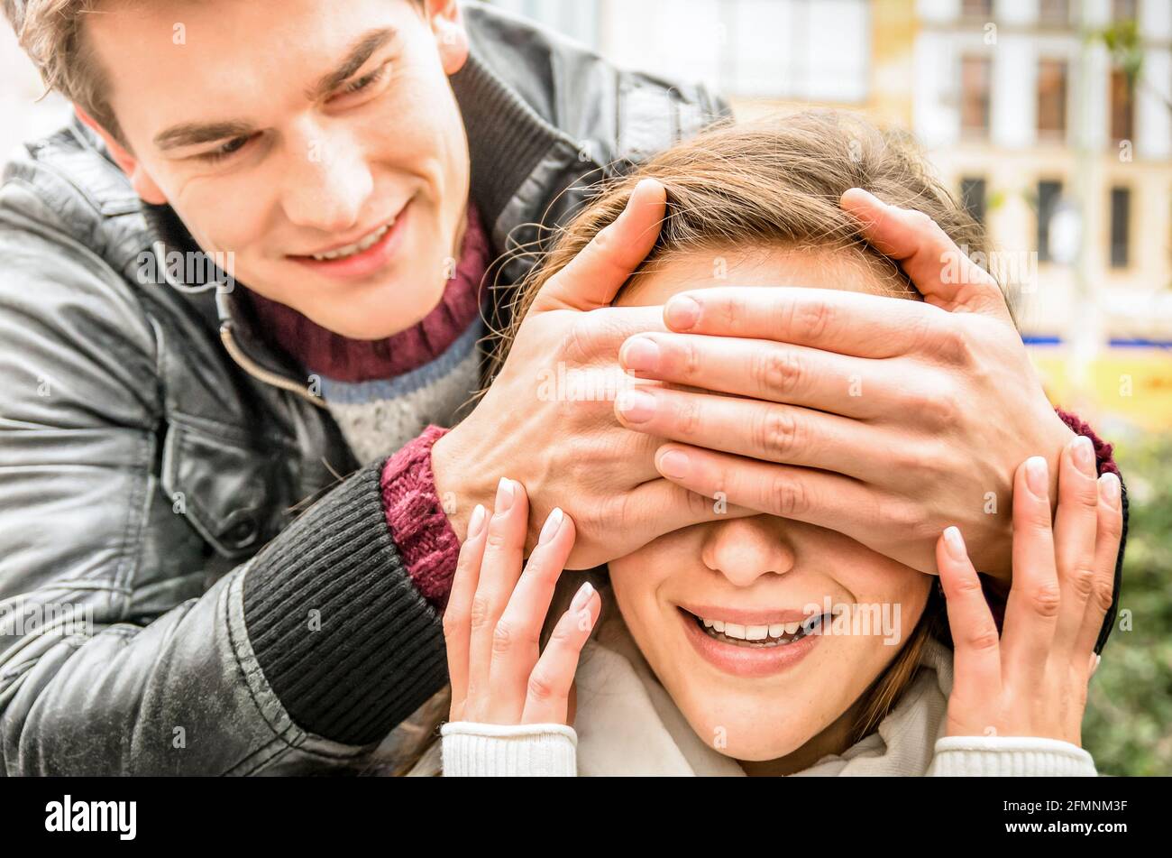 Young man covering the eyes of an happy surprised girlfriend Stock Photo