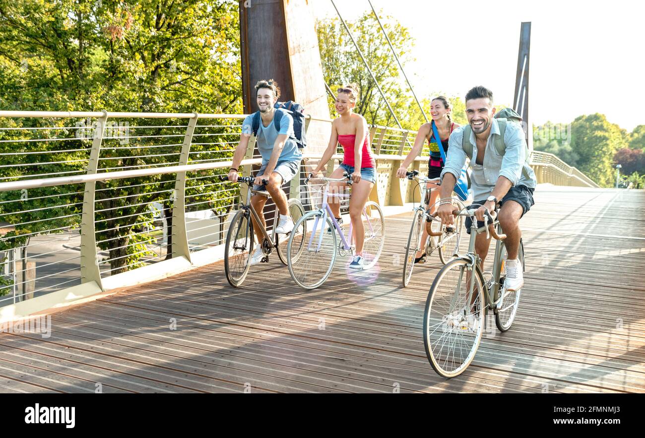 Happy millenial friends having fun riding bike at city park - Friendship concept with young millennial students biking together on bicycle lane Stock Photo