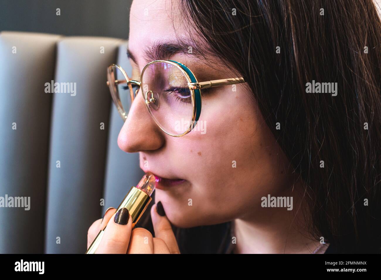 Beautiful girl with glasses applying lipstick Stock Photo