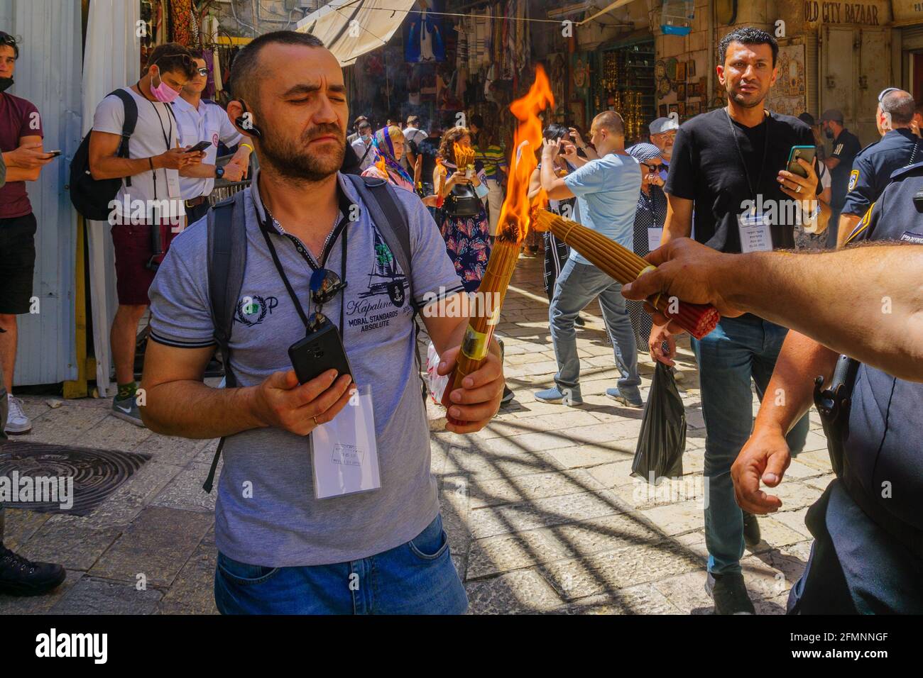 Jerusalem, Israel - May 01, 2021: Pilgrims passing on the Holy Fire, on Holy Saturday (Easter), in the alleys of the Old City around the Holy Sepulchr Stock Photo