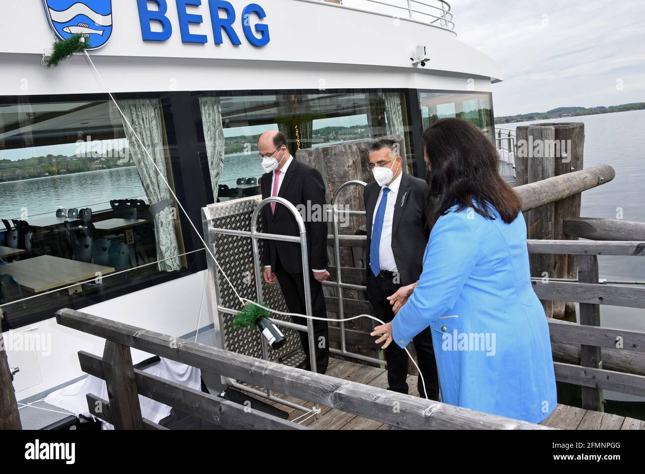 Berg, Germany. 11th May, 2021. Bavarian Finance and Home Affairs Minister Albert Füracker (CSU, l-r), Michael Grießer, Managing Director of Bayerische Seenschifffahrt GmbH, and godmother Ute Eiling-Hütig (CSU) christen the new electric motor ship 'Berg' on Lake Starnberg. The ship holds 300 passengers and, at 35 m long, is the largest fully electric ship on an inland lake in Germany. Credit: Ursula Düren/dpa/Alamy Live News Stock Photo