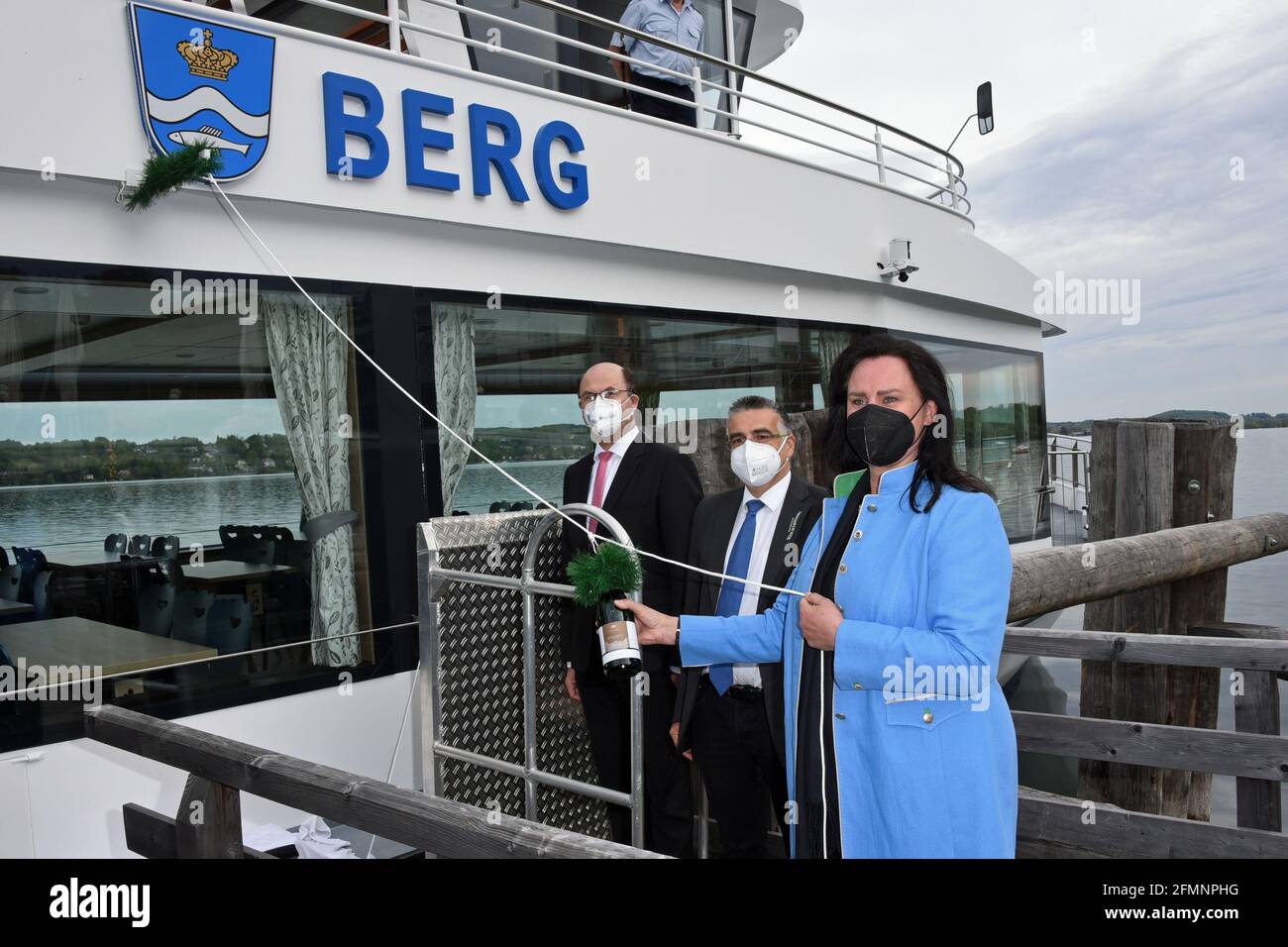 Berg, Germany. 11th May, 2021. Bavarian Finance and Home Affairs Minister Albert Füracker (CSU, l-r), Michael Grießer, Managing Director of Bayerische Seenschifffahrt GmbH, and godmother Ute Eiling-Hütig (CSU) christen the new electric motor ship 'Berg' on Lake Starnberg. The ship holds 300 passengers and, at 35 m long, is the largest fully electric ship on an inland lake in Germany. The ship will be used on the Starnberger Lake. Credit: Ursula Düren/dpa/Alamy Live News Stock Photo