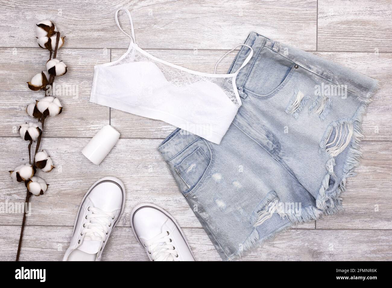 Summer fashion women's outfit. Blue ripped denim shorts, white bra,  sneakers, roll-on deodorant with cotton sprig. Summer essentials Stock  Photo - Alamy