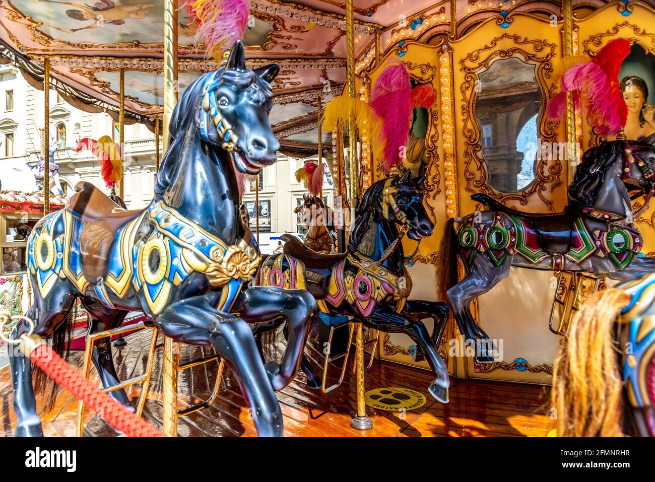 FLORENCE, ITALY - Aug 24, 2020: Florence, Toscana/Italy - 24.08.2020: A very pretty and elaborately decorated children's carousel with black horses an Stock Photo