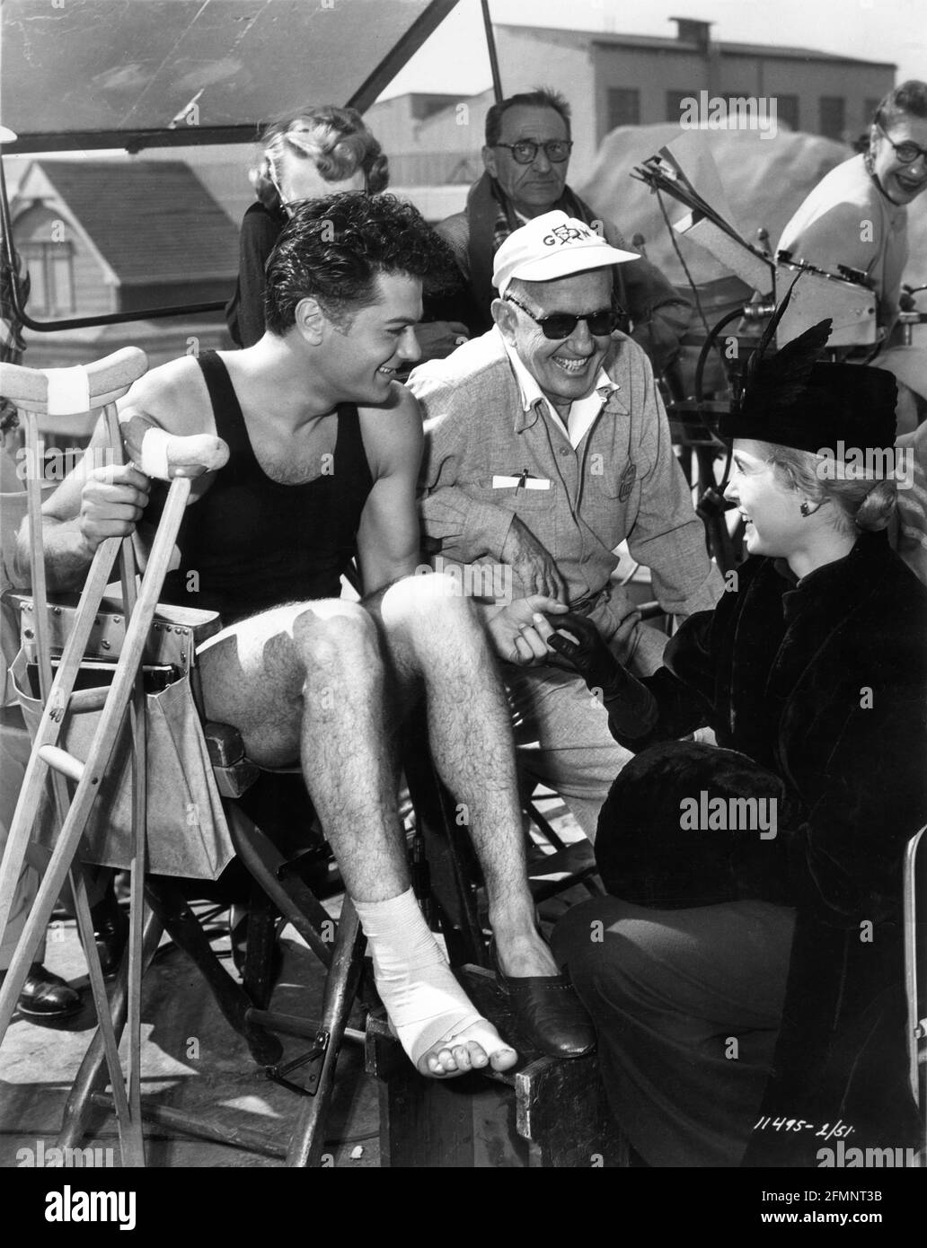 TONY CURTIS in costume as Harry Houdini (with sprained ankle) and his wife and co-star JANET LEIGH on set candid with Director GEORGE MARSHALL and Movie Crew during filming of HOUDINI 1953 director GEORGE MARSHALL book Harold Kellock screenplay Philip Yordan producer George Pal Paramount Pictures Stock Photo