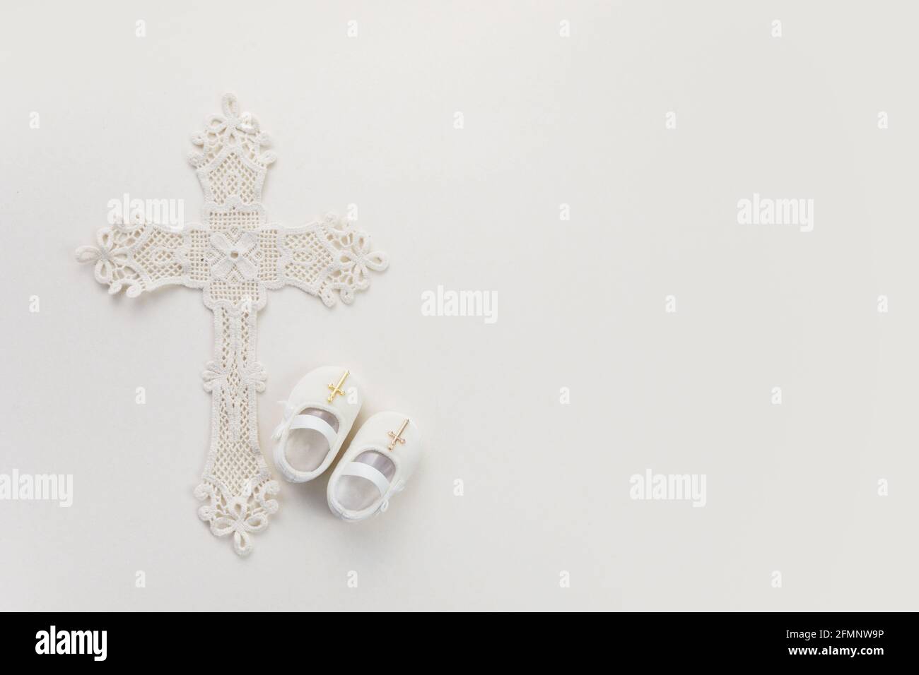Christening background with baptism baby shoes, and cross on pastel