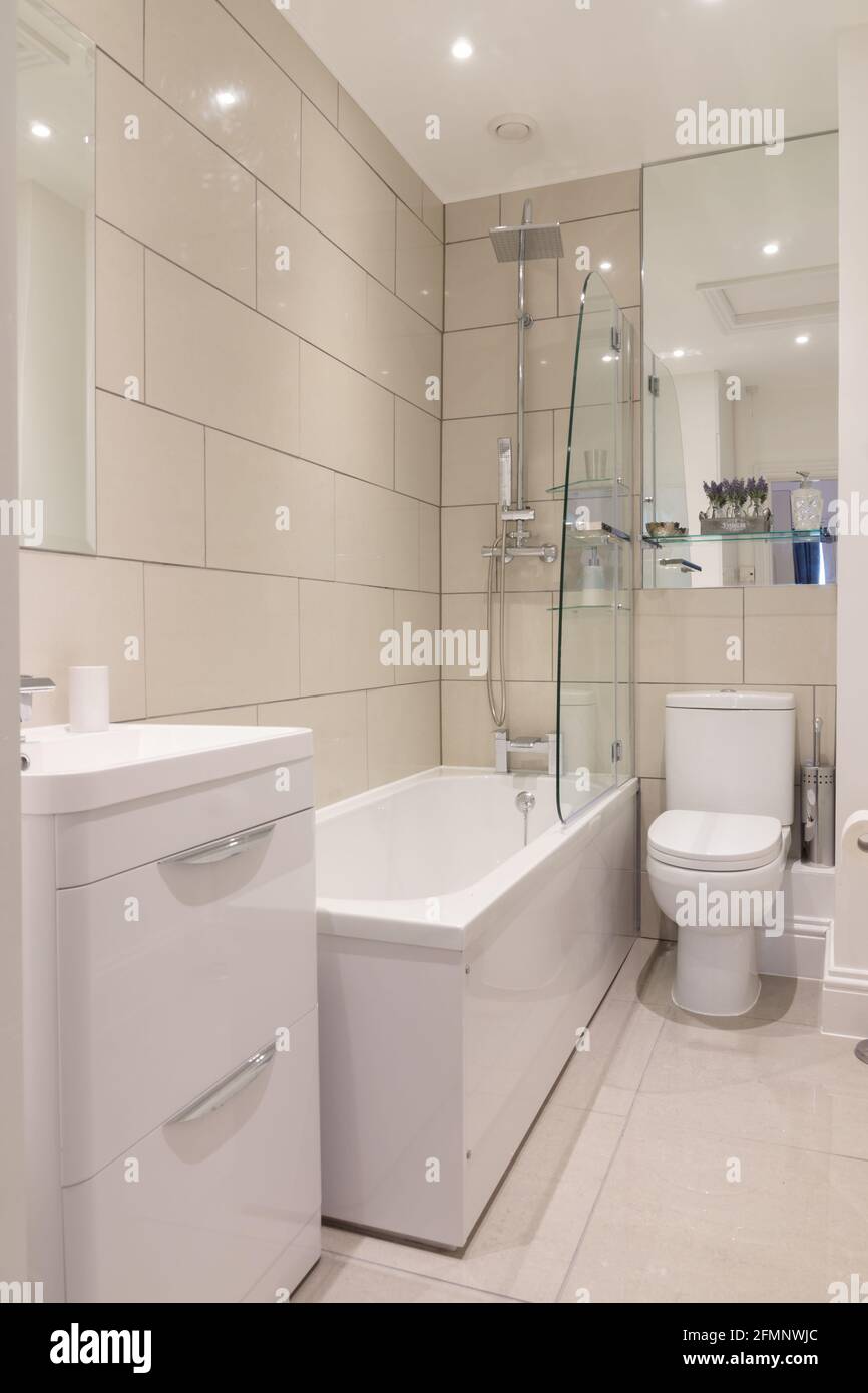 A stylish modern tiled bathroom with bath built in shower and toilet Stock Photo