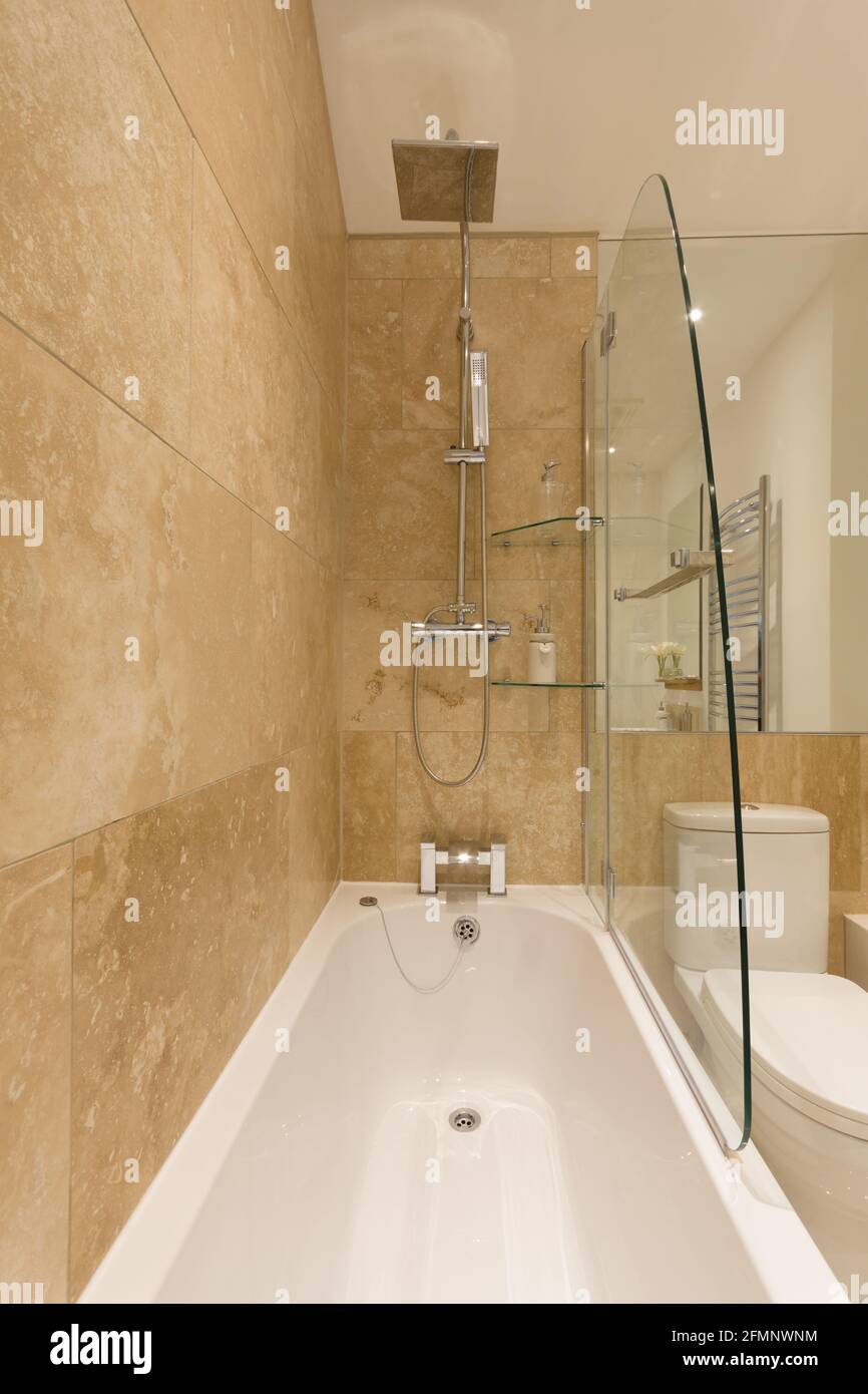 A stylish modern bathroom with built in shower cubicle bath tub and toilet Stock Photo