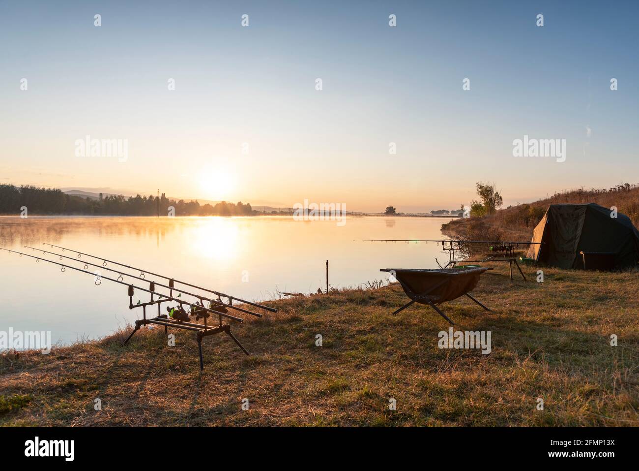 Fishing rods and reels set up with electronic bite alarms by the side of a  lake; the bite indicators sound when fish bite Stock Photo - Alamy