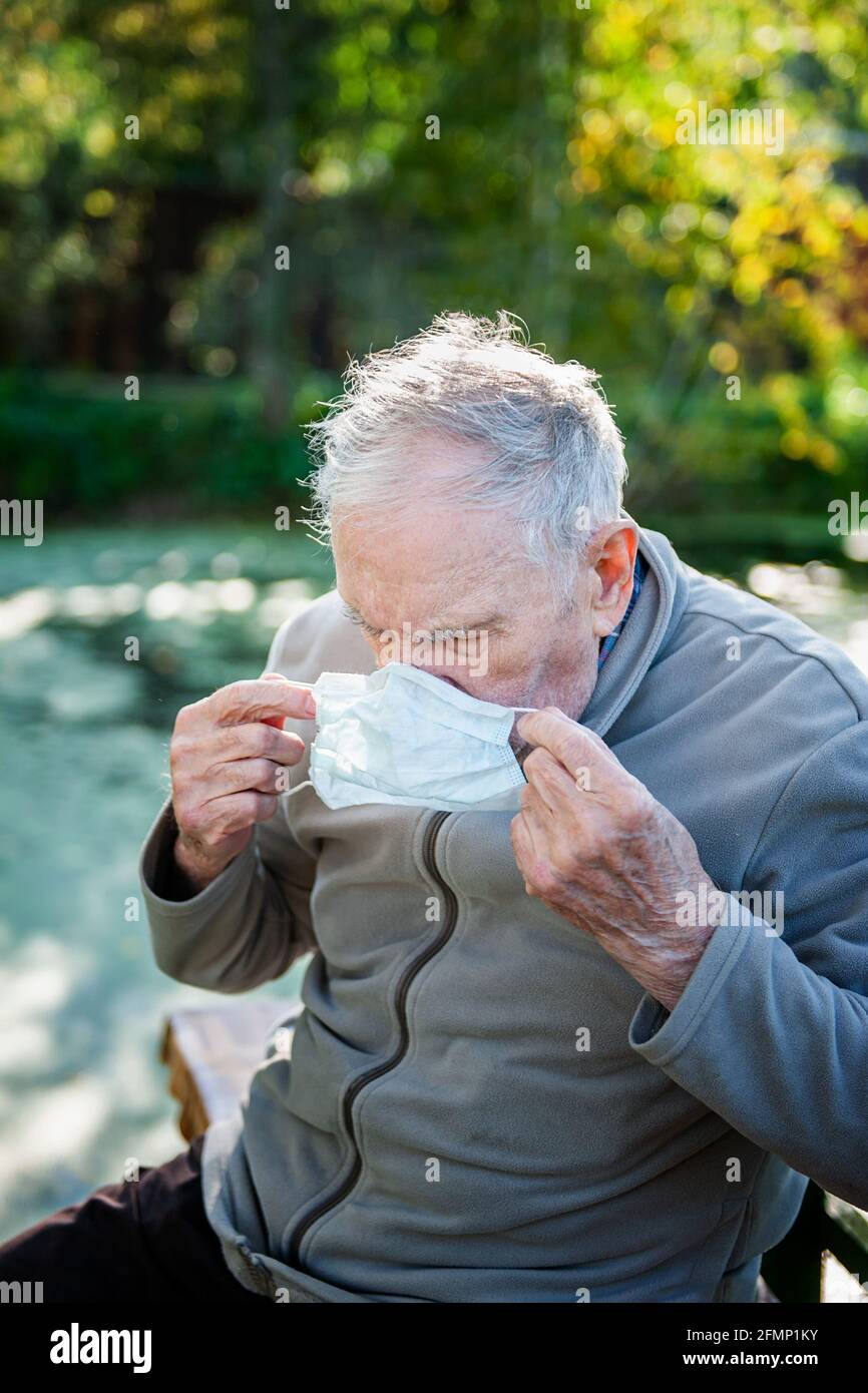 an-old-87-year-old-man-puts-on-a-mask-while-sitting-outside-protection