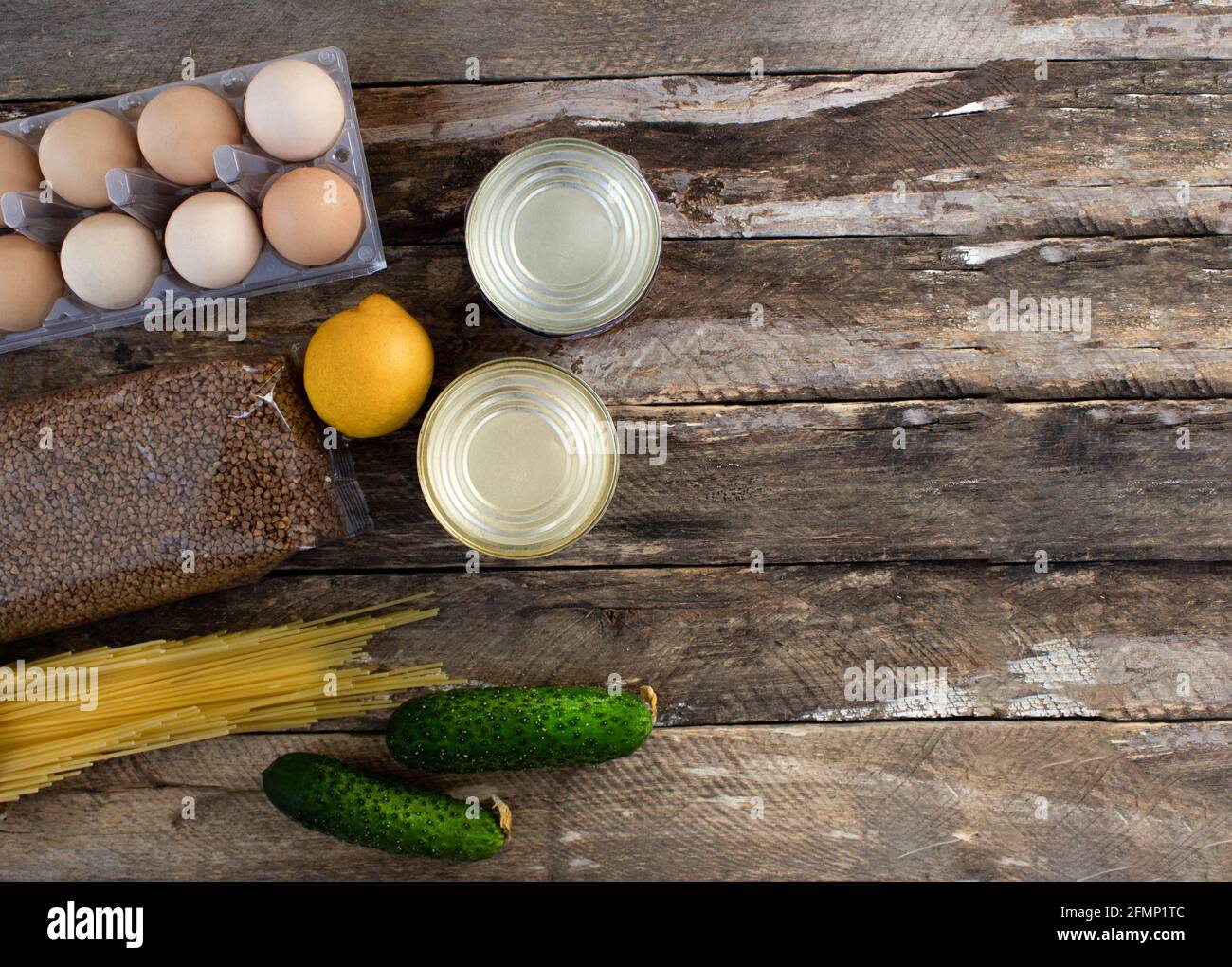 Food supplies. Buying food on a wooden background. Eggs, canned food, pasta, vegetables on a wooden background Stock Photo