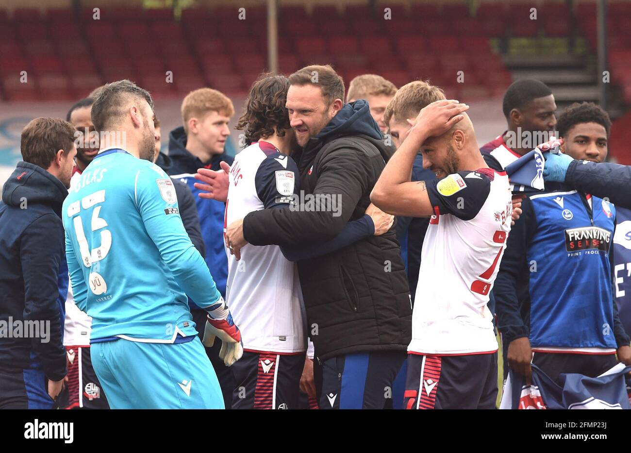 Bolton manager Ian Evatt hugs his players as they celebrate promotion after their 4-1 win against Crawley in the Sky Bet League Two match between Crawley Town and Bolton Wanderers at the People's Pension Stadium  , Crawley ,  UK - 8th May 2021 -  EDITORIAL USE ONLY No use with unauthorised audio, video, data, fixture lists, club/league logos or “live” services. Online in-match use limited to 120 images, no video emulation. No use in betting, games or single club/league/player publications Stock Photo