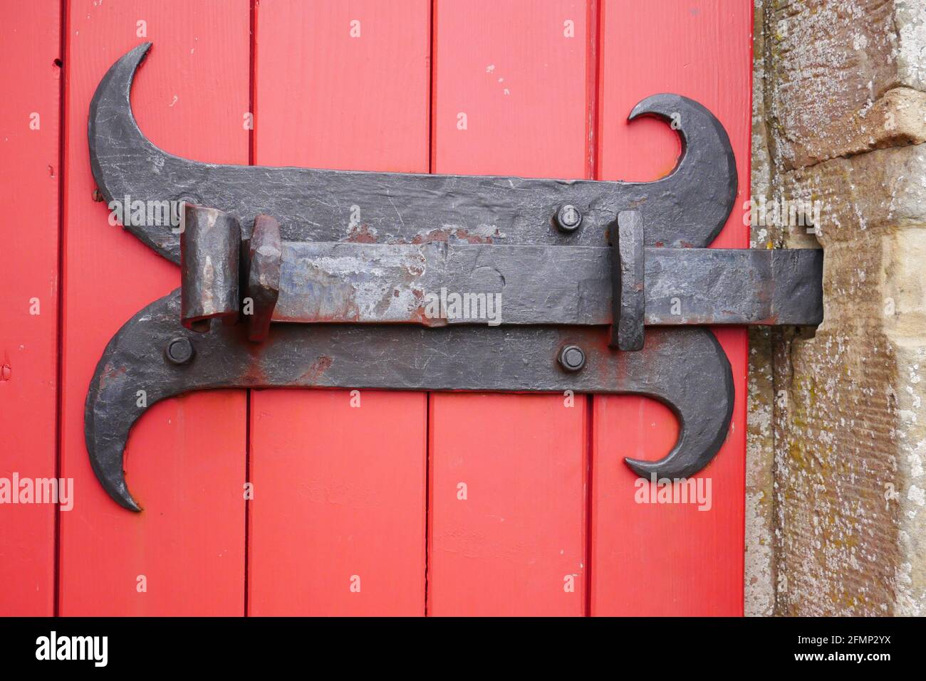 old ornate metal locking bolt as a door lock on a red wooden door of a
