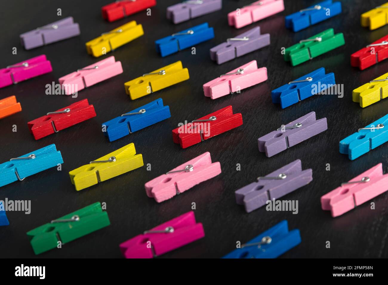 Bright multi-colored clothespins on black background. Diversity. Stock Photo
