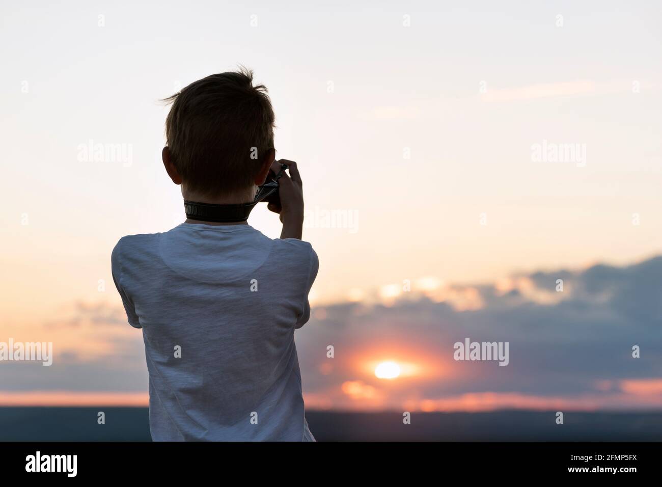 Boy photographs the sunset. Child with camera on setting sun background ...