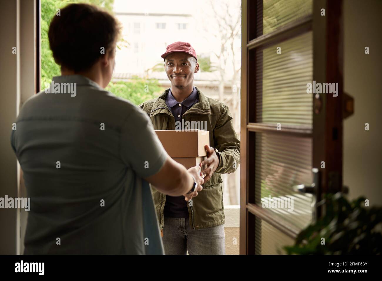 African courier smiling while delivering packages to a customer Stock Photo
