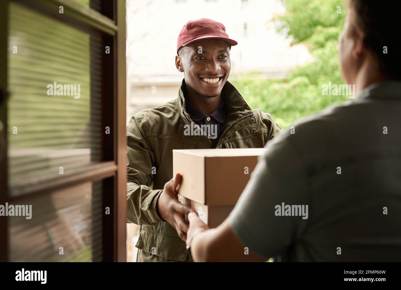 African courier smiling while delivering packages to a client Stock Photo