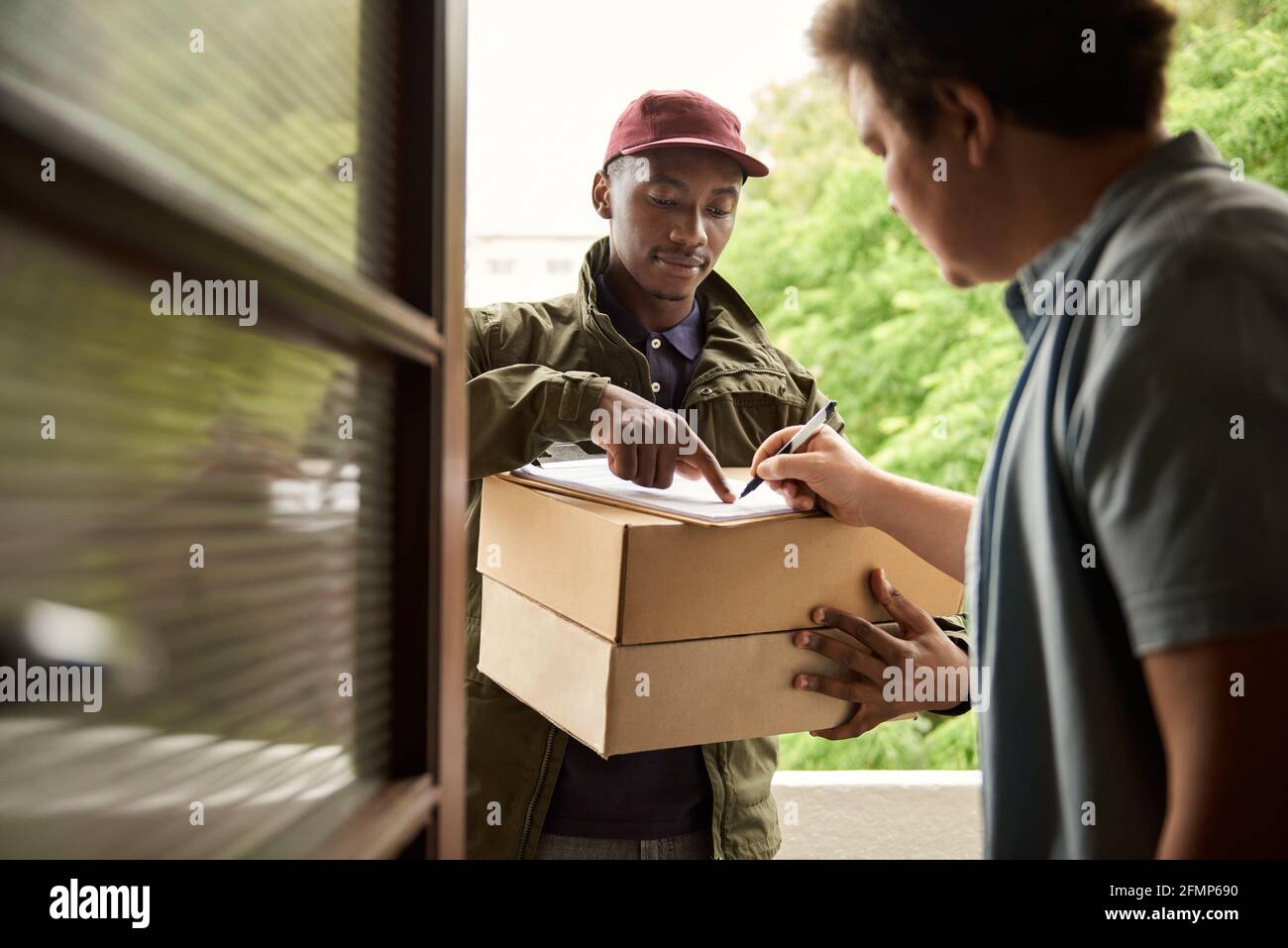Man signing for a courier delivery at his front door Stock Photo