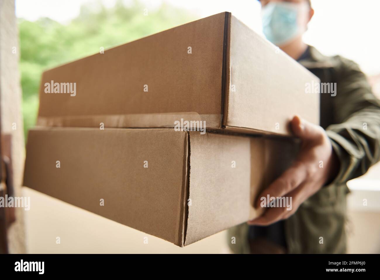 Delivery man holding up packages at a customer's door Stock Photo
