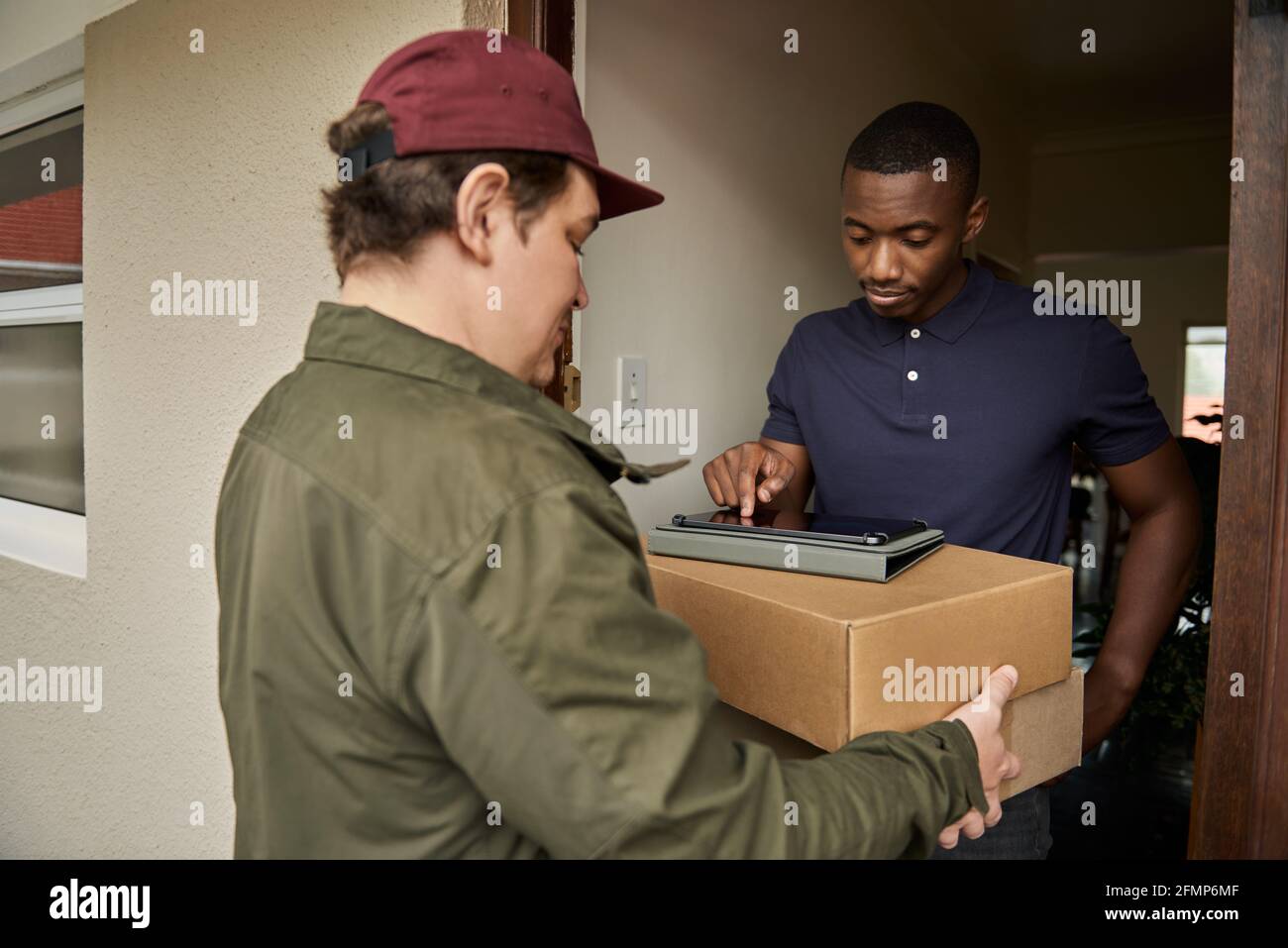 African man digitally signing a courier's tablet for a delivery Stock Photo