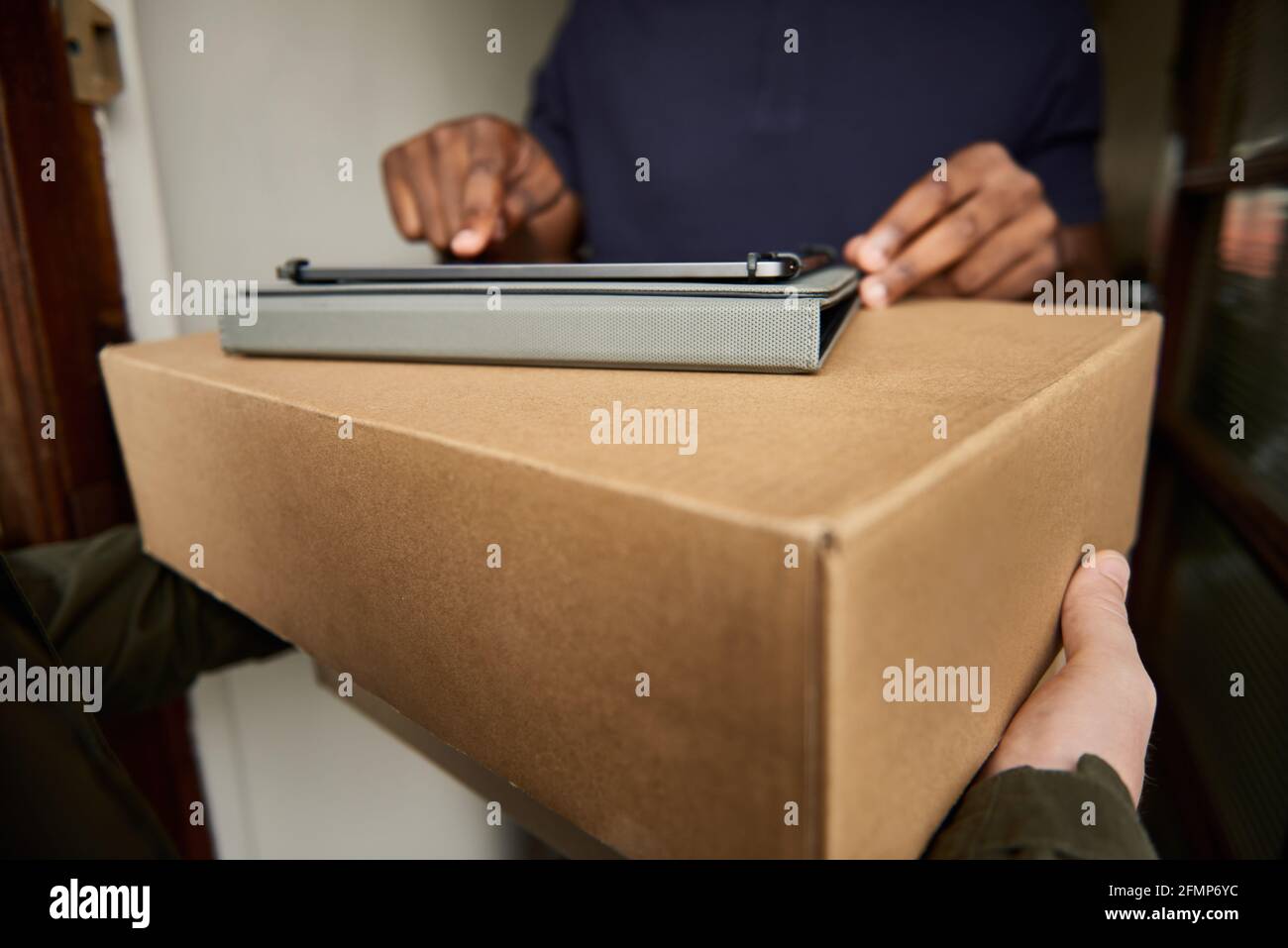 African man digitally signing a tablet for a courier delivery Stock Photo