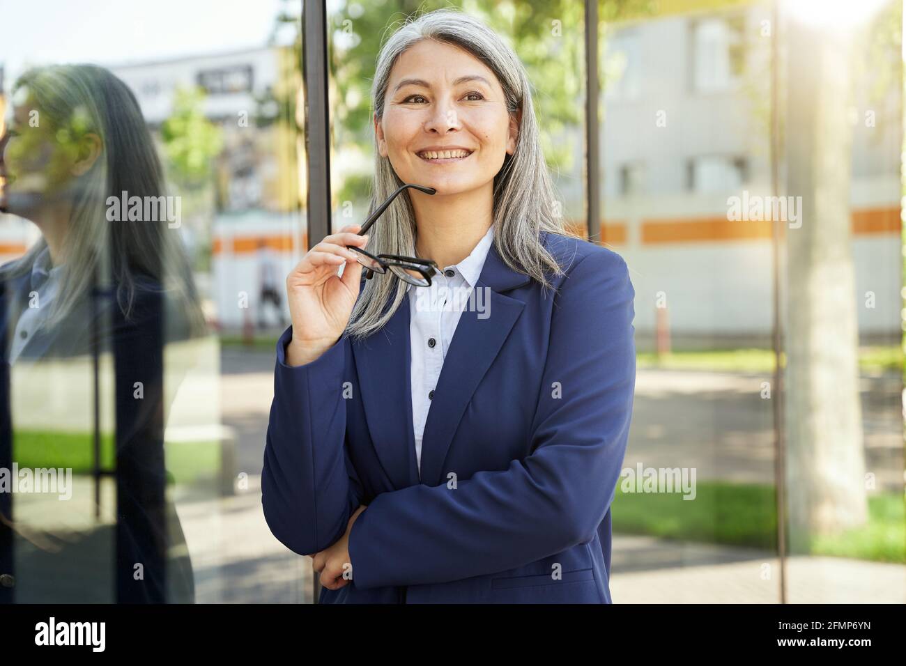 Positive mature lady holding eye glasses and smiling Stock Photo