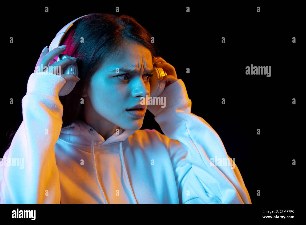 Portrait of young beautiful girl in headphones isolated over dark ...