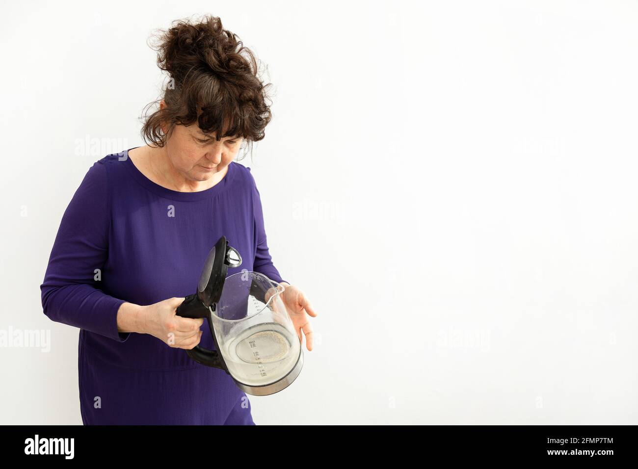 Woman holds electric kettle with limescale in her hands. Chalk residue