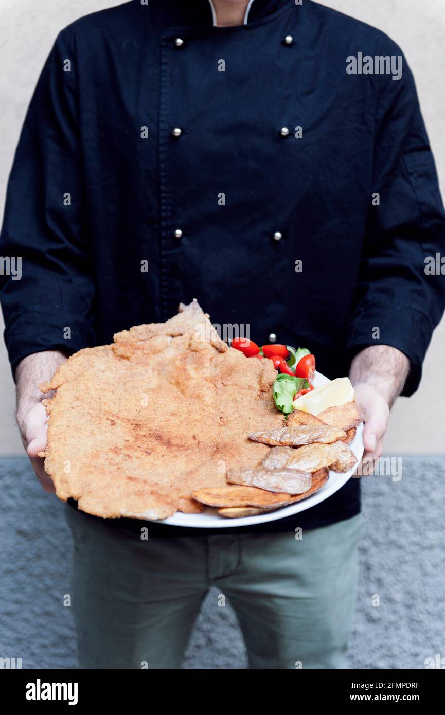 Cotoletta Milanese cooked by Restaurant Damm atra in Milano served with fried potatoes skind and tomatoes salad, Milan, Italy, Europe Stock Photo