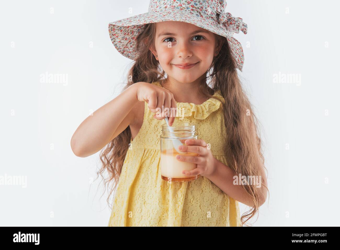 Beautiful little girl eating tasty cream dessert portrait isolated on white background. Stock Photo