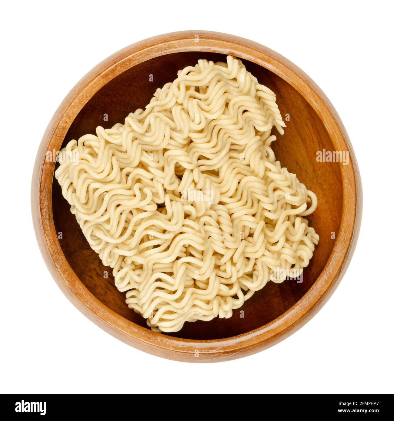 Dried instant noodles in a wooden bowl. Instant ramen are noodles sold in precooked and dried block form,  to be soaked in boiling water. Stock Photo