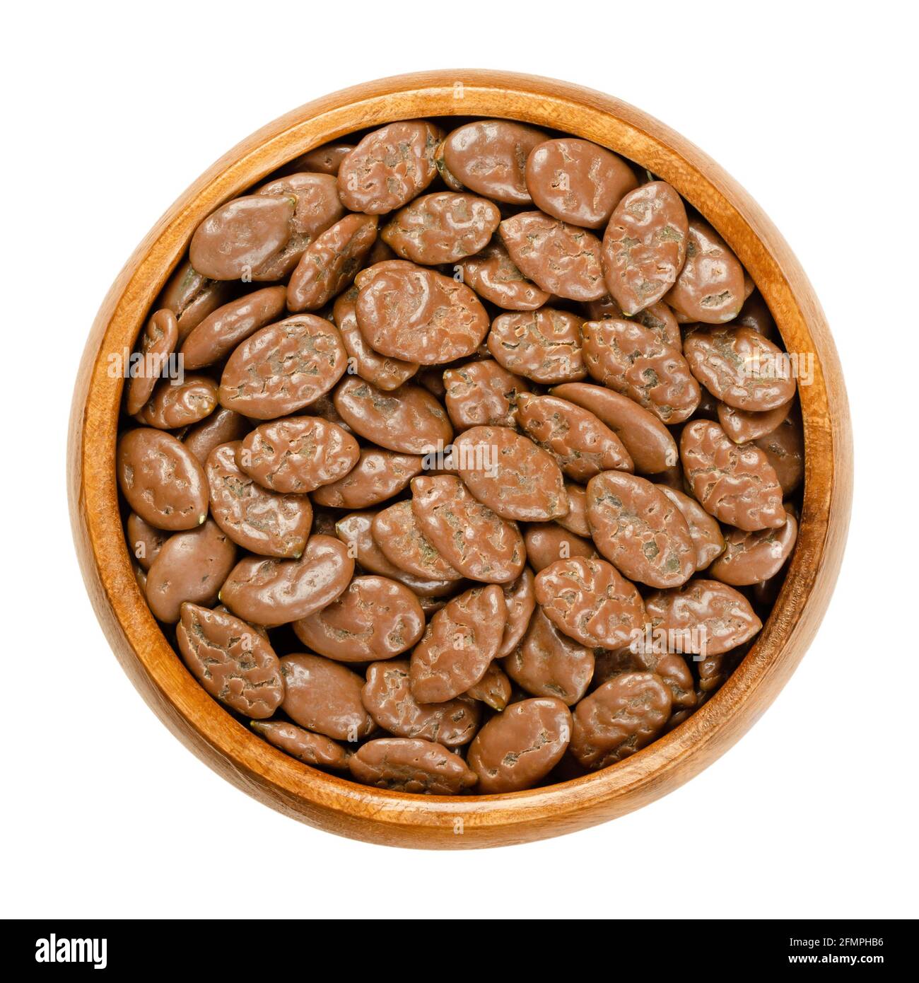 Roasted pumpkin seeds, coated with milk chocolate, in a wooden bowl. Snack of flat summer squash seeds, lightly roasted, and covered with chocolate. Stock Photo