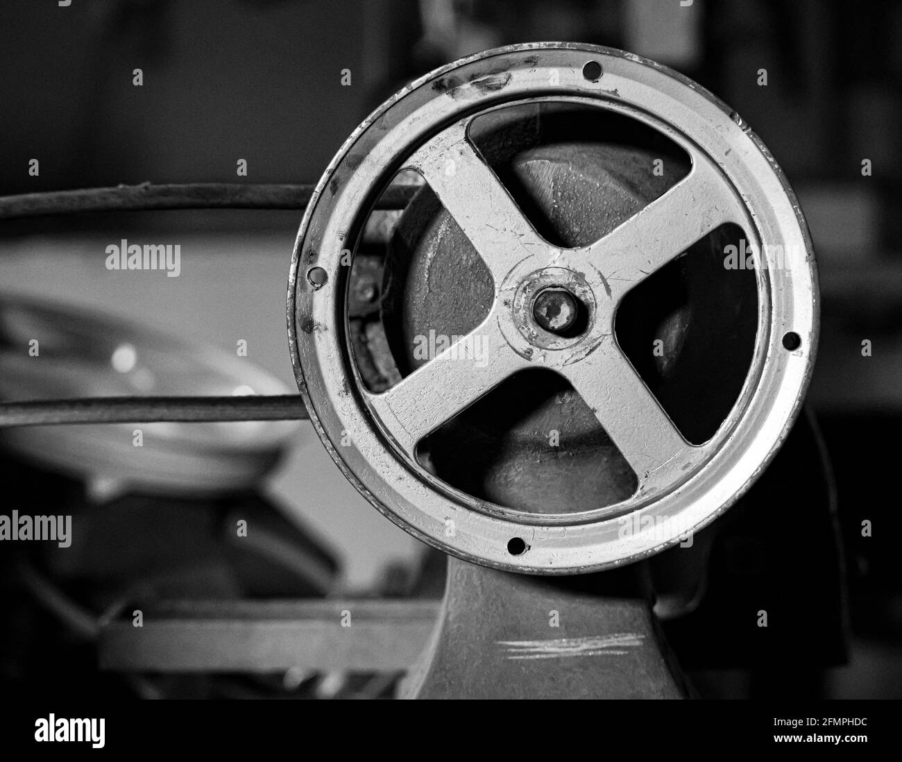 A pulley from an old woodworking lathe machine in a house basement taken in black and white Stock Photo