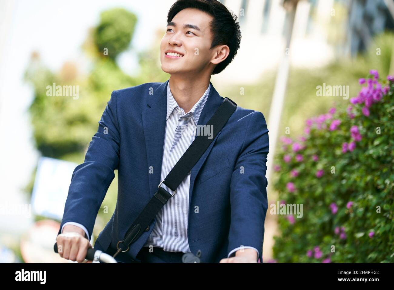 young asian business man riding bicycle to or from work, happy and smiling Stock Photo