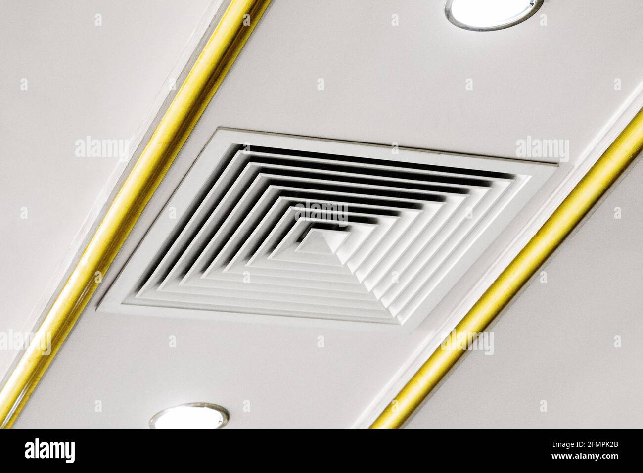 Square ventilation grill on the ceiling next to a spotlight. Stock Photo