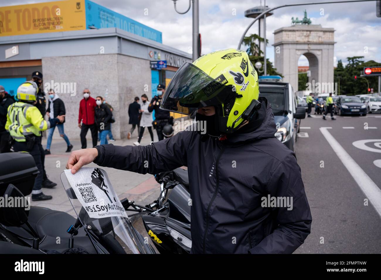 A delivery man in front of Puerta de Moncloa, puts a sticker on his motorcycle during the demonstration.Dozens of 'riders' (food distributors) demonstrate, claiming their work as a freelancer and against the conditions of delivery companies such as Globo and Deliveroo. This morning Spain approved the 'Riders Law' and gave companies a period of 3 months to hire people instead of having them as false freelancers. The Minister of Labor and Social Economy, Yolanda Díaz, pointed out that Spain is going to be the first country to have a standard on digital platforms. (Photo by Diego Radames/SOPA I Stock Photo