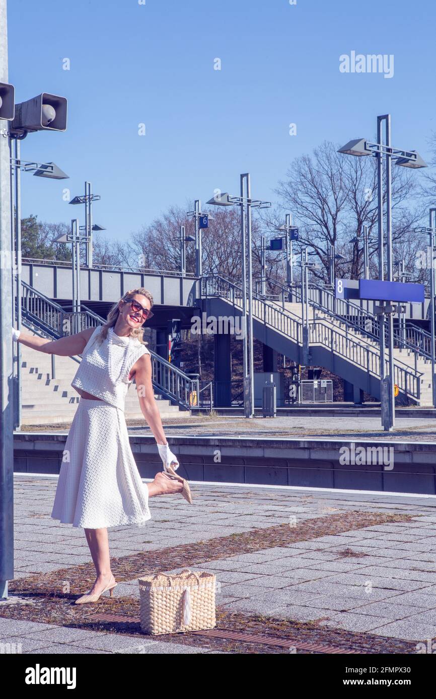blonde woman in white dress standing at train station Stock Photo - Alamy