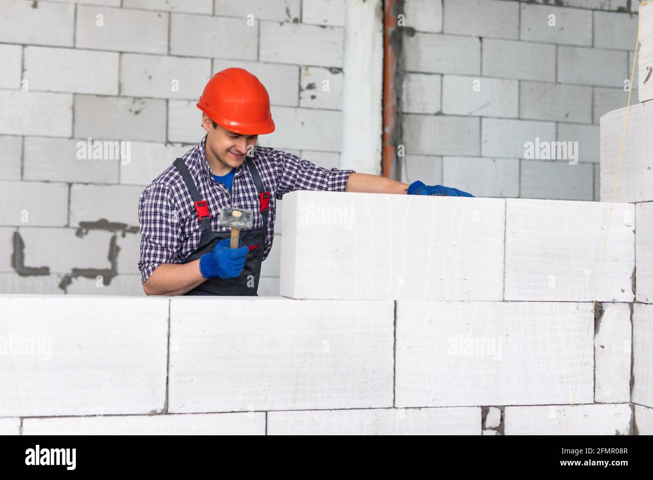 bricklayer man builder working with autoclaved aerated concrete blocks. Walling Stock Photo