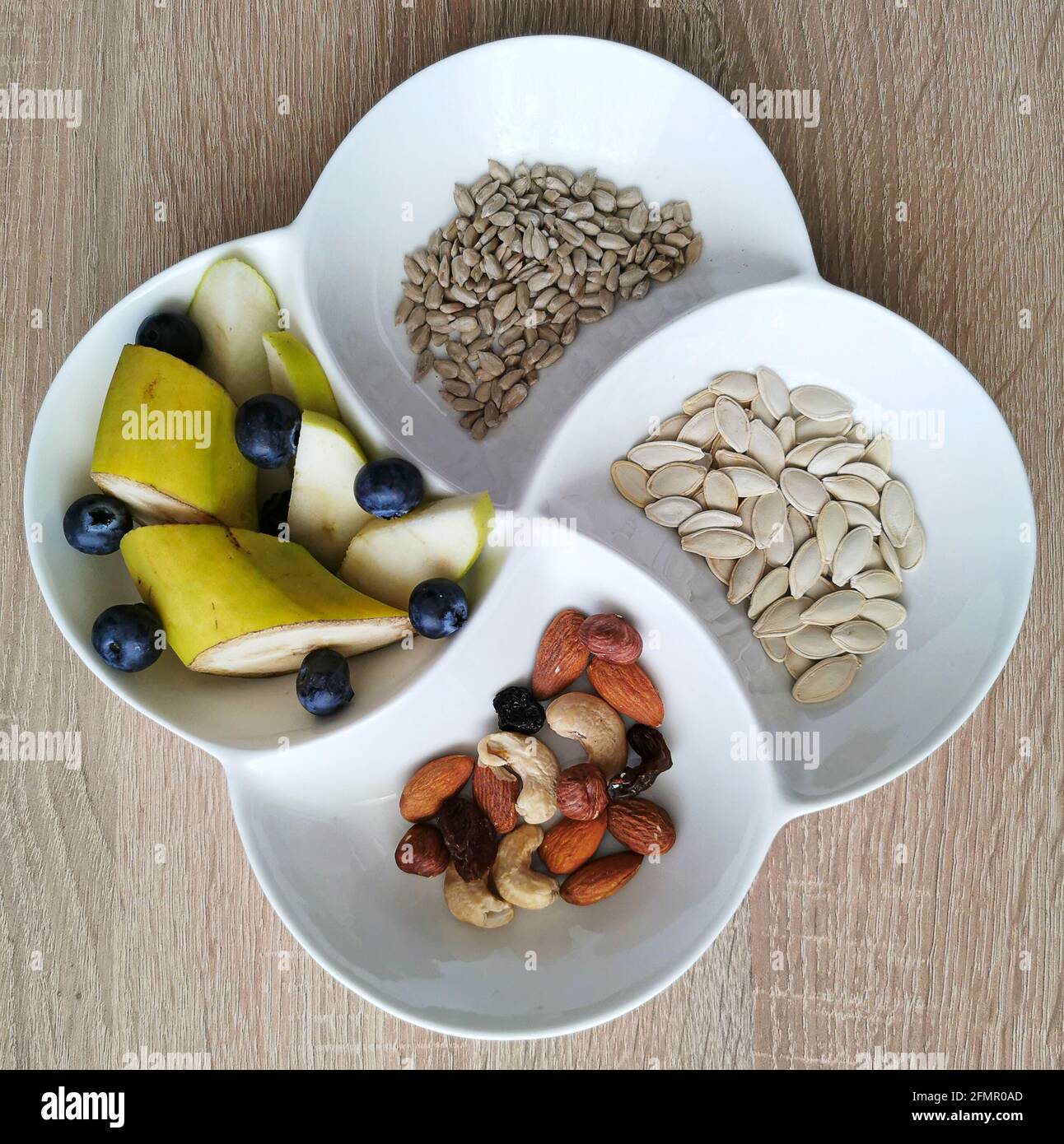 A healthy snack. Nuts, sunflower and pumpkin seeds. Banana pieces, apples and blueberries Stock Photo