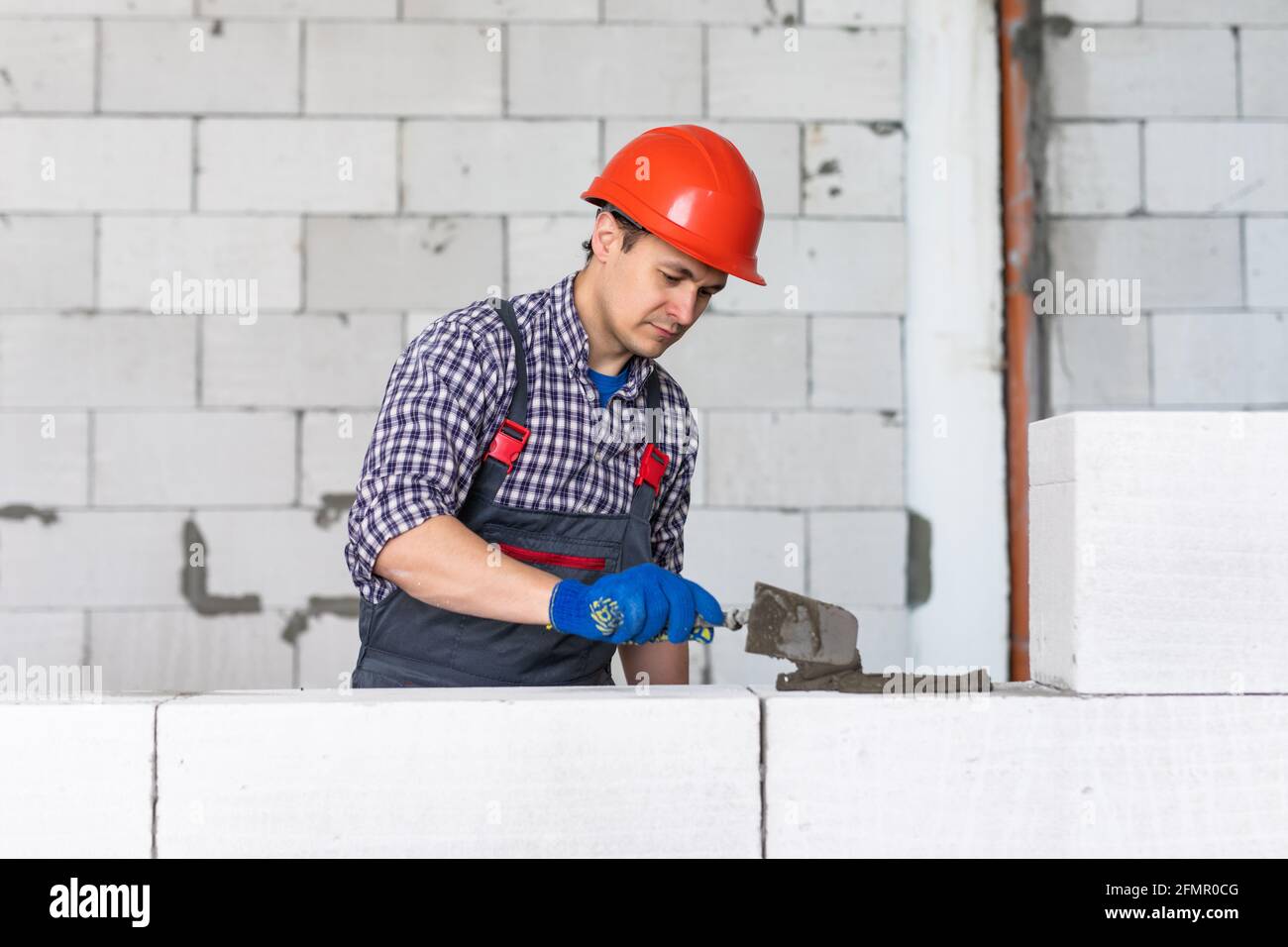 The process of bricklaying. Mason hands installing aerated concrete wall using special glue and