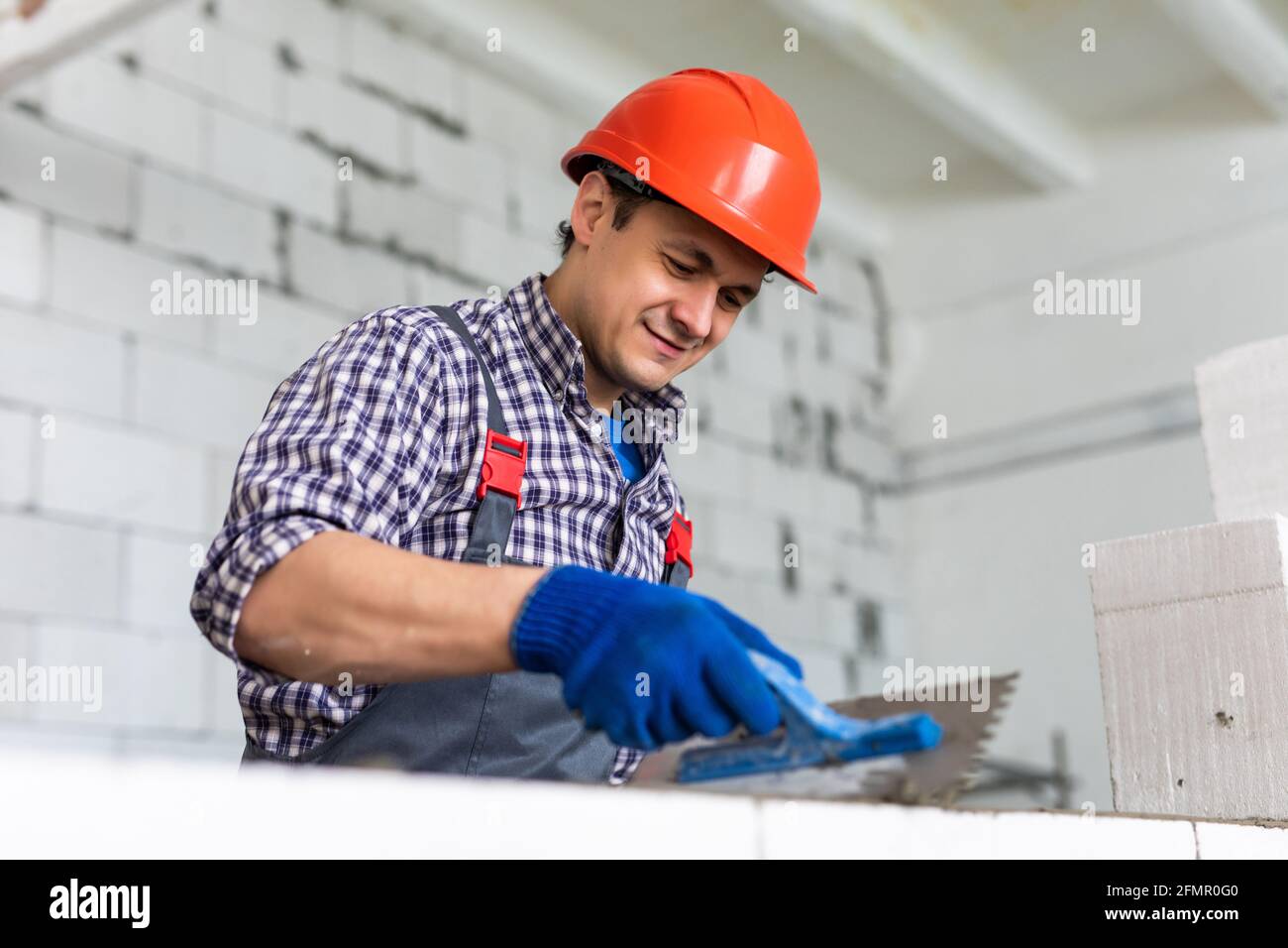 The process of bricklaying. Mason hands installing aerated concrete