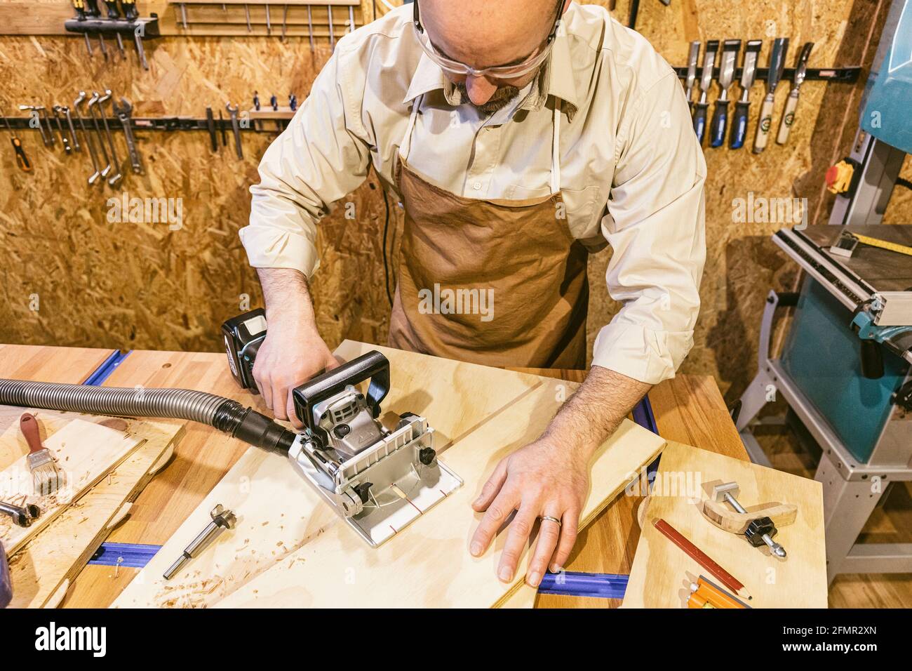 carpenter who uses a biscuit jointer inside his workshop. Stock Photo